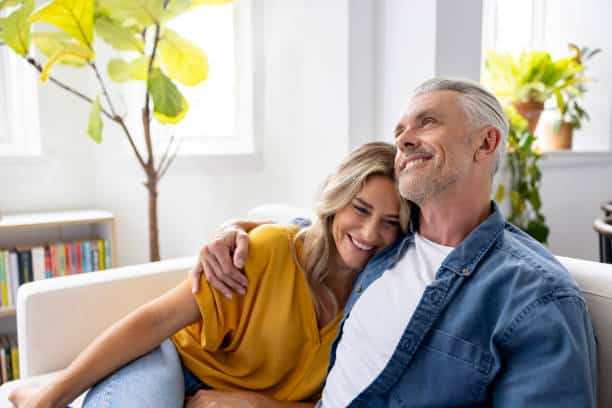 Man and woman with their arms wrapped around each other on the couch.