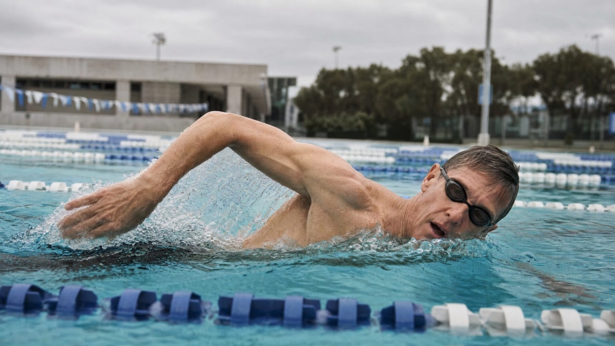 Older man swimming laps in a pool.