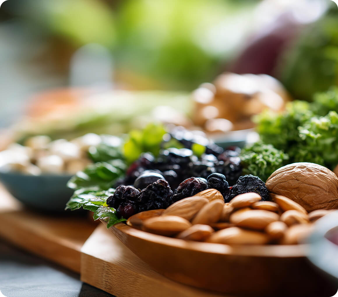 Healthy nuts and berries on a wooden platter with fresh greens in the background