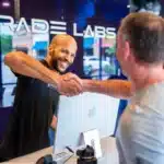 two men shaking hands near a computer, in front of an Upgrade Labs sign