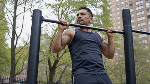 Man performing pull-ups on outdoor exercise bar in park